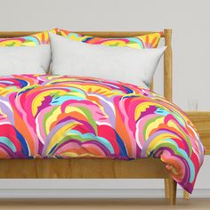 a bed with colorful comforters and pillows on it