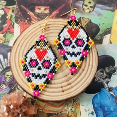 a pair of beaded earrings sitting on top of a piece of wood next to a rock and roll