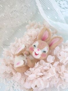 there is a small stuffed animal in the middle of some pink flowers and white lace