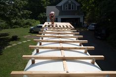 a man standing on top of a wooden structure in the grass next to a house