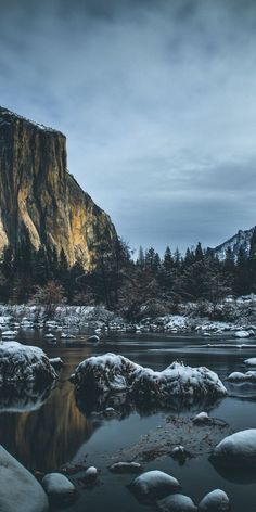 the mountains are covered in snow and ice as it sits next to a body of water