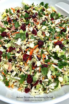 a salad with cranberries, celery, carrots and lettuce in a white bowl