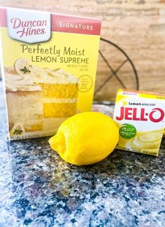 two boxes of jello next to a lemon on a table with a piece of cake