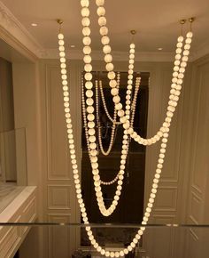 a chandelier made out of white beads hanging from the ceiling in a bathroom