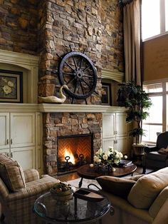 a living room filled with furniture and a fire place in front of a stone wall