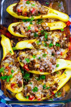 stuffed bell peppers with meat and cheese in a casserole dish on a blue checkered cloth