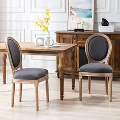 a dining room table with two chairs and a vase on top of it in front of a dresser