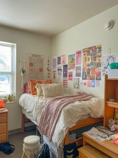 a bed room with a neatly made bed and lots of pictures on the wall above it