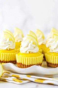 lemon cupcakes with white frosting on a plate next to a slice of lemon