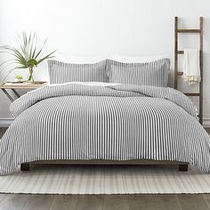 a bed with black and white striped comforter in a room next to a plant