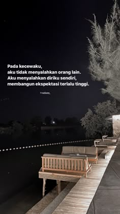 there is a bench sitting on the edge of a pier at night with an inspirational quote above it