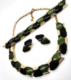 Black and green Lucite gold toned mid century vintage demi parure set. Fair vintage condition with some signs of wear. Gold toned setting has some chips and plating loss on the bracelet and necklace as seen in pictures. Bracelet measures 1/2 of an inch tall and 6.5 inches long. Earrings measure 1 and 1/8th of an inch tall and 3/4ths of an inch wide. Necklace measures 17.5 inches long and 1/2 of an inch wide. Black Vintage Jewelry With Multicolored Beads, Vintage Green Double Strand Necklace, Antique Green Multi-stone Jewelry, Vintage Green Multi-strand Necklace, Vintage Gold Clip-on Earrings With Black Enamel, Mid Century Vintage, Gold Tones, Mid Century, Green