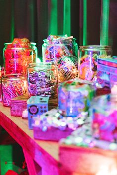 there are many glass jars on the table with candy in them and one is filled with candies