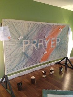 a large sign that says prayer on it in front of some paint cans and brushes