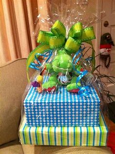 a green stuffed animal sitting on top of two wrapped presents