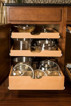 an open cabinet with pots and pans in it