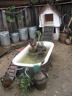 a tub filled with water next to a wooden fence and potted plants in it