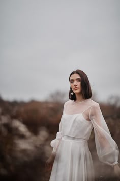 a woman in a white dress is standing on the ground with her hands behind her back