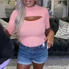 a woman in pink shirt and denim shorts