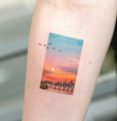 a sunset with birds flying in the sky and an image of a city on it