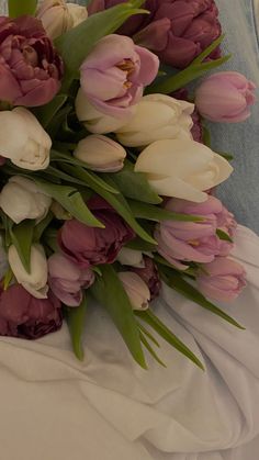 a bouquet of pink and white tulips on a bed