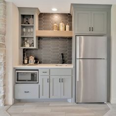 a kitchen with gray cabinets and white tile flooring is shown in this image, there are shelves above the refrigerator