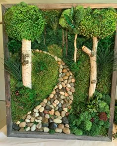 a wooden frame with moss and rocks in the shape of a path between two trees