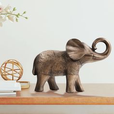 an elephant figurine sitting on top of a table next to a vase with flowers