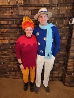 two people dressed up in costumes standing next to each other, one wearing an orange and blue hat