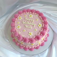 a birthday cake with pink frosting and white flowers on the top that says happy birthday heart