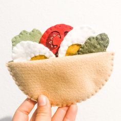 a hand holding a small felt bowl with food in it