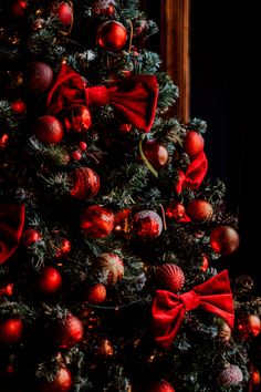 a decorated christmas tree with red bows and baubles on it's branches