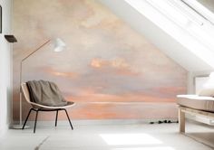 a room with a bed, chair and sky mural on the wall in it's corner