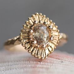 a close up view of a gold ring with an oval shaped diamond in the center