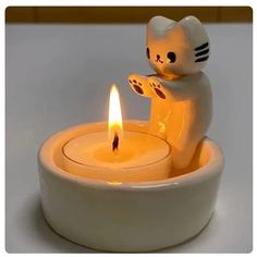 a cat candle holder with a lit candle in it