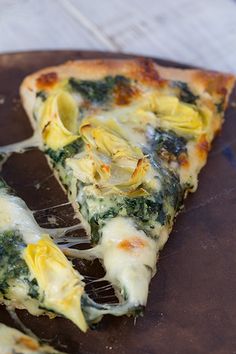 a slice of spinach and artichoke pizza on a plate with a fork