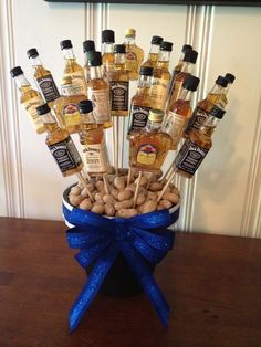 a vase filled with lots of bottles of liquor on top of a wooden table next to a blue ribbon