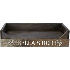 a wooden tray with the words bella's bed and paw prints in white on it