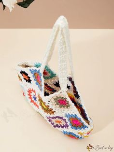 a crocheted bag with handles is sitting on a table next to a flower