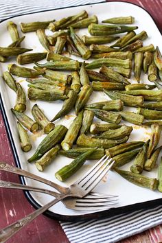 a white plate topped with green beans next to a fork