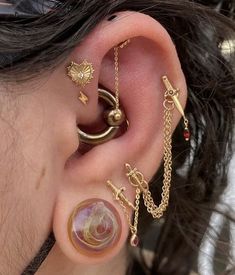 a woman wearing gold ear piercings and chains