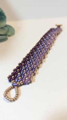 This Herringbone style beaded bracelet is created with SuperDuo Czech Glass Beads and Japanese Toho and Miyuki Round Beads. It features a combination of multi-tone purples and a gold color button clasp.  *This bracelet is 7" long and It has a width of .75". Purple Beaded Pearl Bracelet With Round Beads, Handmade Adjustable Oval Beaded Bracelets, Handmade Adjustable Beaded Bracelets With Oval Beads, Handmade Bracelets With Round Beads, Handmade Purple Pearl Bracelet With Round Beads, Czech Glass Beads, Herringbone, Czech Glass, Round Beads