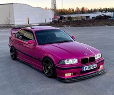 a pink car parked in a parking lot