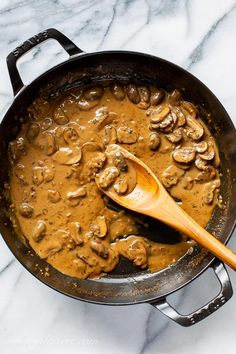 a skillet filled with mushrooms and gravy on top of a marble counter