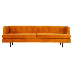 an orange couch sitting on top of a white wall