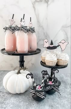 three cupcakes and two drinks are sitting on a cake stand with halloween decorations