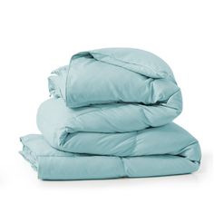 a stack of blue sheets and pillows on top of each other in front of a white background