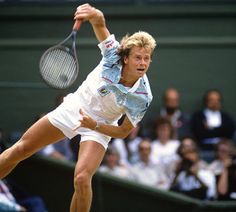 a man swinging a tennis racquet on top of a tennis court in front of an audience