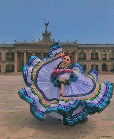 a woman in a colorful dress is standing on the ground with her arms spread out