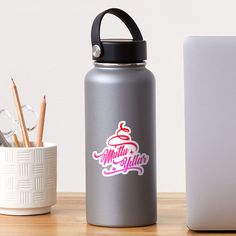 a silver water bottle sitting on top of a wooden table next to a white laptop